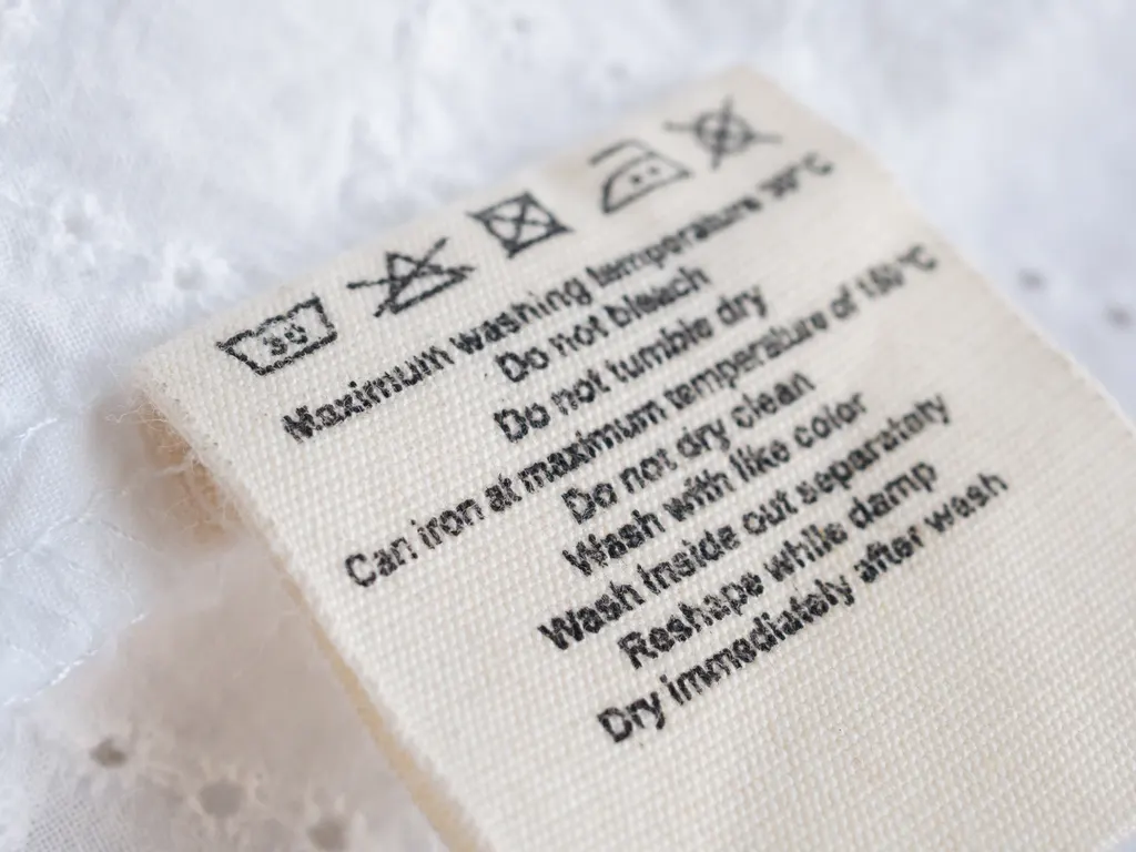 Close-up of a sewn-in garment care label printed with laundry symbols and washing instructions